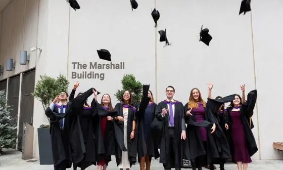 A group of students wearing graduation gowns throwing caps in the air.